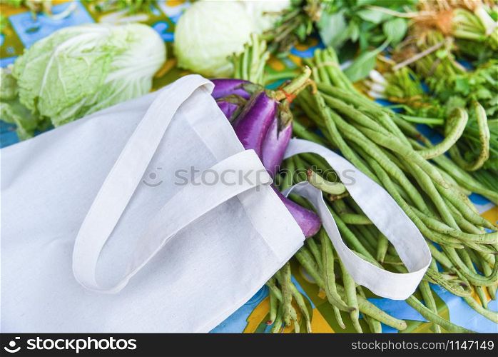 Zero waste use less plastic say no plastic bag concept / Fresh vegetables organic in eco cotton fabric bags on table - white tote canvas cloth bag from market free plastic shopping