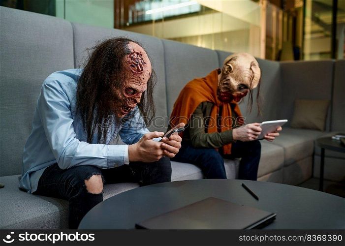 Zombie employees relaxing with digital gadgets sitting on sofa. Office worker rest during work break in lobby of business building. Coworking open space. Zombie employees relaxing with gadgets sitting on sofa