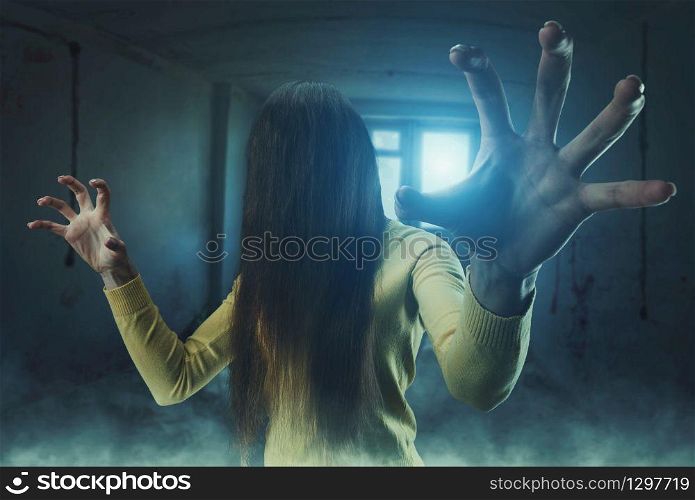 Zombie girl with long hair in her face in an abandoned building