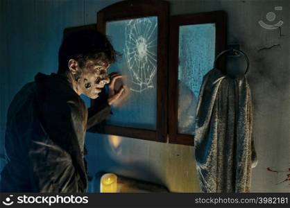 Zombie monster man front of broken mirror in haunted house. Terrified sinister person portrait. Zombie monster man front of broken mirror