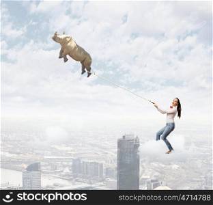 Zoo animal. Young woman holding flying rhino on rope
