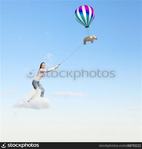 Zoo animal. Young woman holding flying rhino on rope