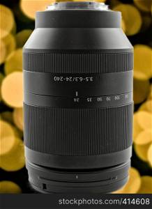 Zoom lens with a focal length of 24 to 240 mm in front of a background with yellow and orange bokeh.