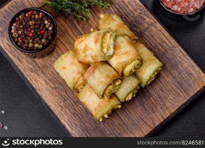 Zucchini appetizer rolls with cream cheese and eggs on a cutting board on dark gray background. Low carbs Zucchini pockets filled with savory spinach, eggs and cheese