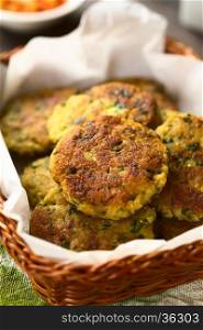 Zucchini, couscous and parsley fritters in basket, photographed with natural light (Selective Focus, Focus in the middle of the top fritter)