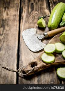 Zucchini with a knife for cutting . On wooden background.. Zucchini with a knife for cutting .