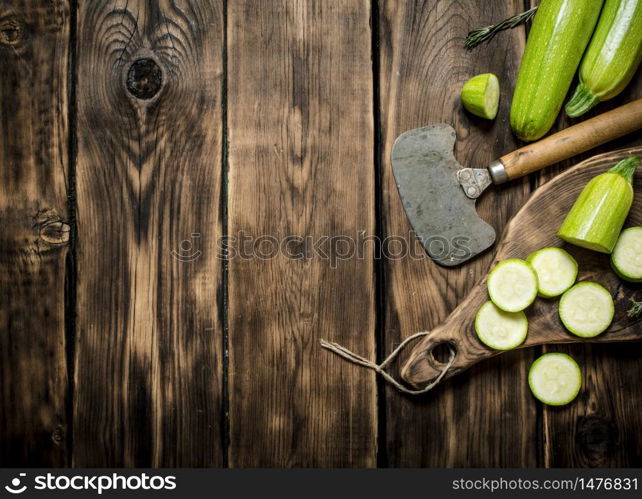 Zucchini with a knife for cutting . On wooden background.. Zucchini with a knife for cutting .