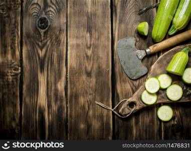 Zucchini with a knife for cutting . On wooden background.. Zucchini with a knife for cutting .