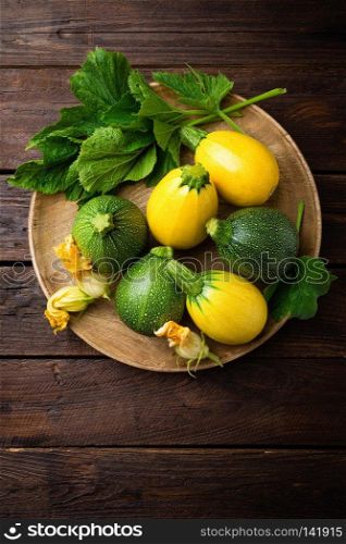 Zucchini with leaves and flowers on dark wooden rustic background
