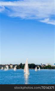 Zurich, Switzerland - Peaceful lake shore and beautiful white sailing boats in lake Zurich on clear sky day in early autumn